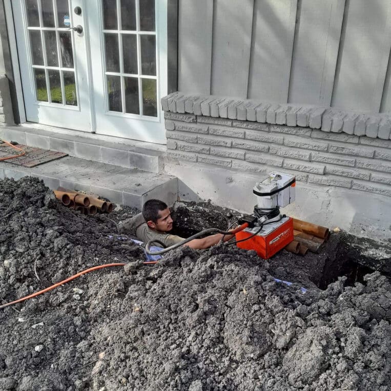 hercules repair technician standing in a shoulder-deep hole along the outer edge of a texas home's concrete slab foundation