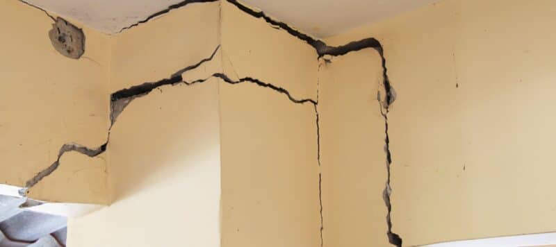 two parallel curved line cracks in the drywall towards the ceiling inside a home