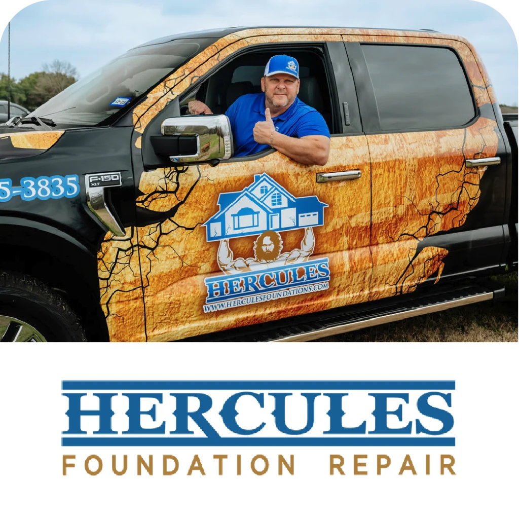 Man in a blue shirt giving a thumbs-up while sitting in a Hercules Foundation Repair truck wrapped in a cracked-earth design